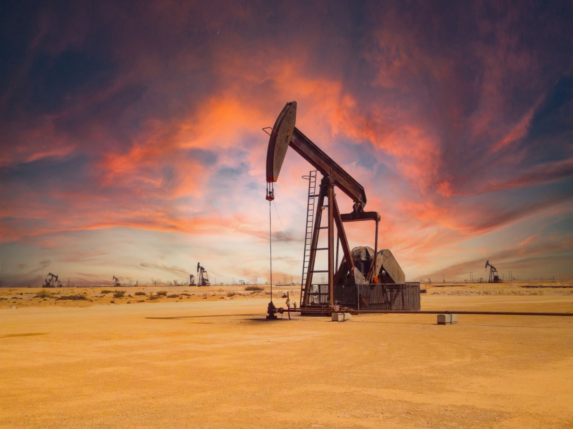 Oil pump jack at sunset in desert
